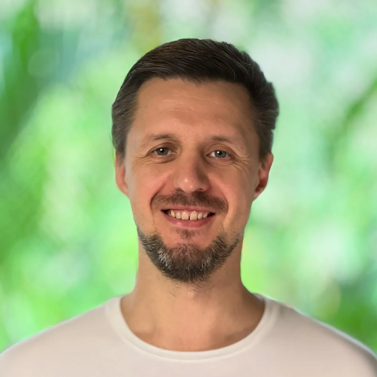 Portrait of Alex Samson smiling, against a green background